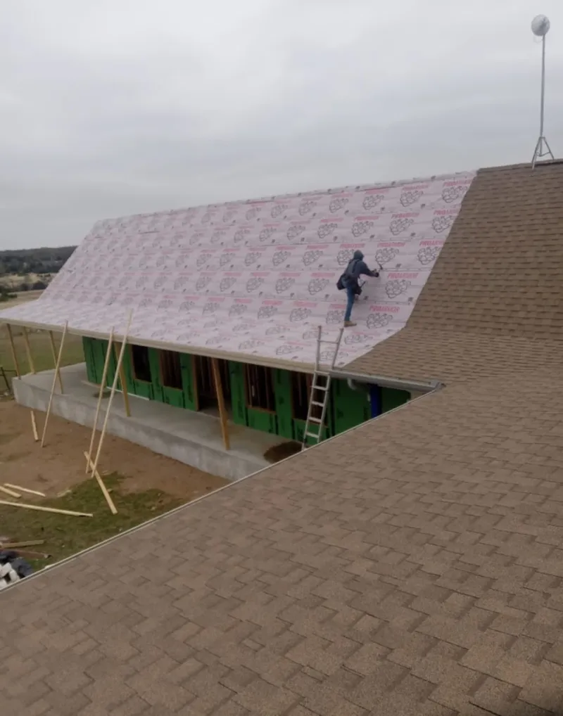 Worker preparing underlayment for a metal roof installation in Farmington Hills